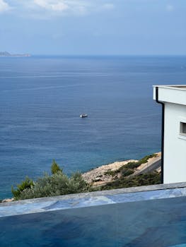 豪华的无边泳池旁，海景宁静而美丽，一艘孤独的船静静地漂浮在水面上