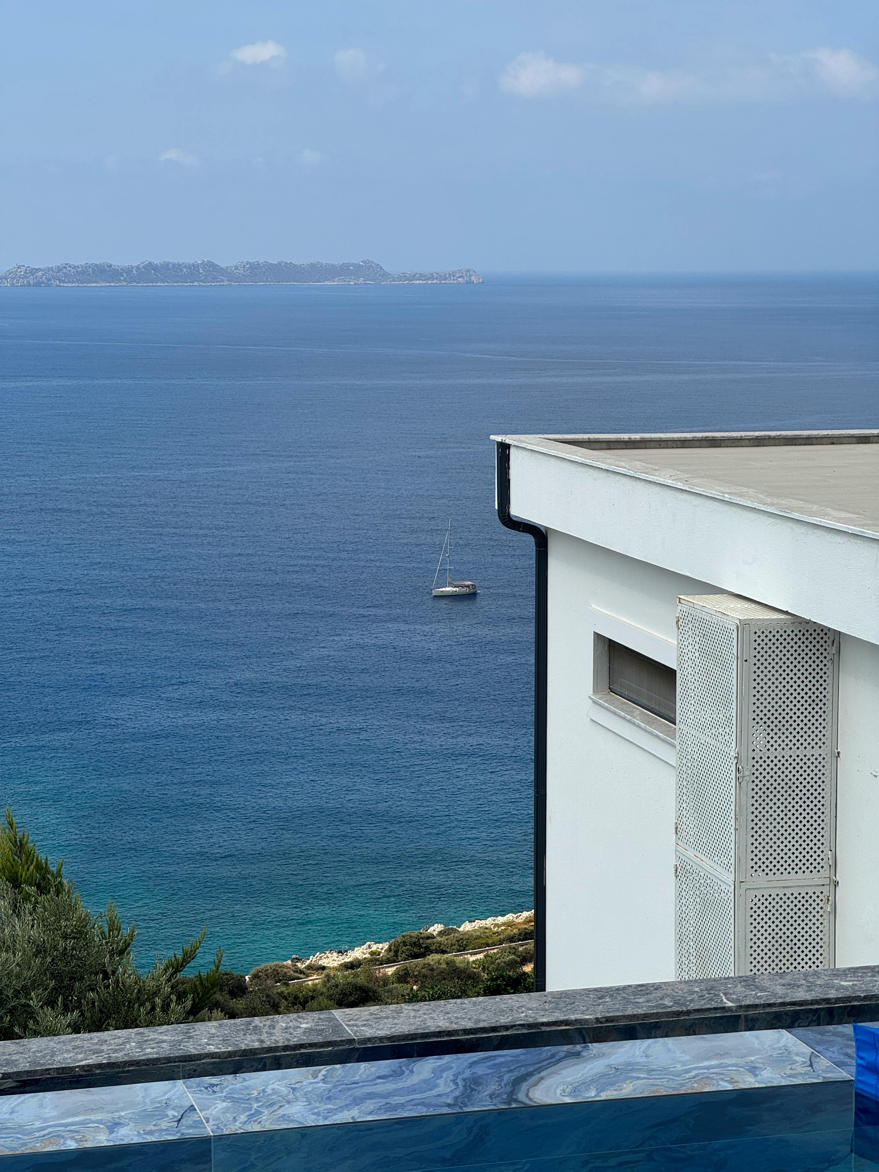 宁静的海岸景观，远处有游艇和现代建筑，非常适合放松身心