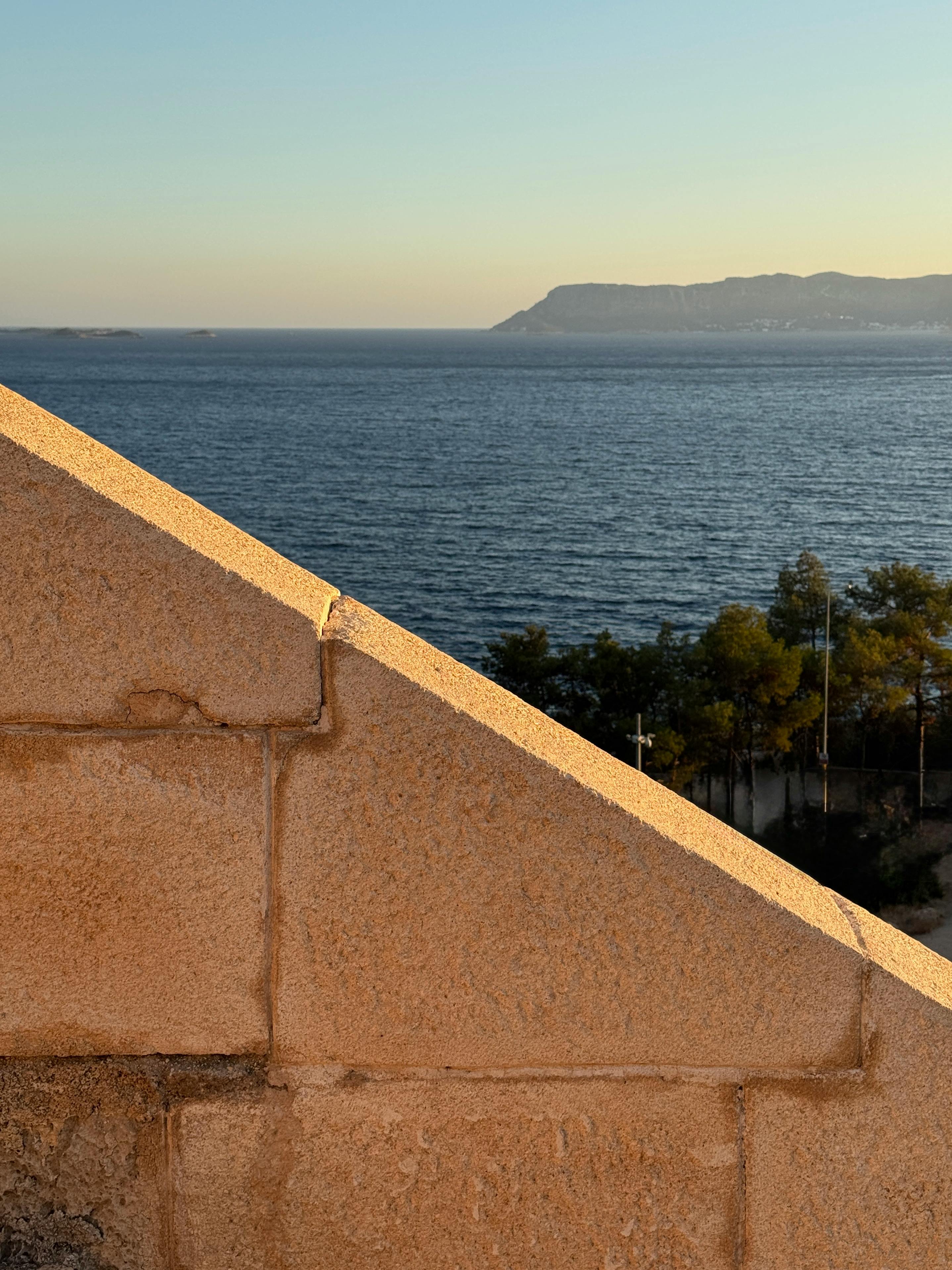 在宁静的海滨，石头结构的建筑俯瞰着日落时分的深蓝色海水