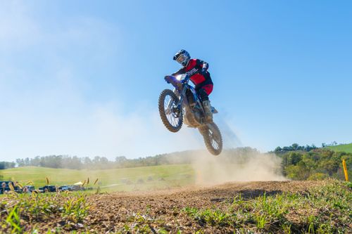 Free Dynamic action shot of a motocross rider executing a thrilling jump on a dirt bike amid a scenic outdoor track. Stock Photo