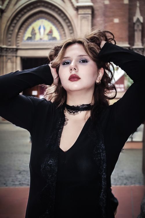Free A fashionable woman poses confidently in front of an ornate historic building's entrance. Stock Photo