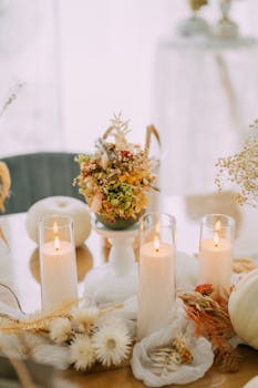 Charming fall-themed table setup with lit candles and dried floral arrangement for a cozy ambiance.