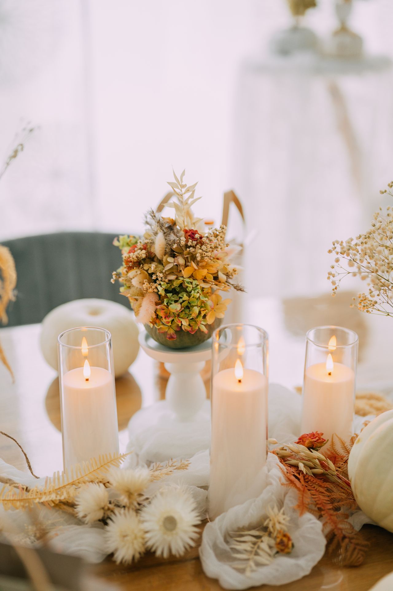 Elegant fall table with white candles, dried florals and white pumpkins