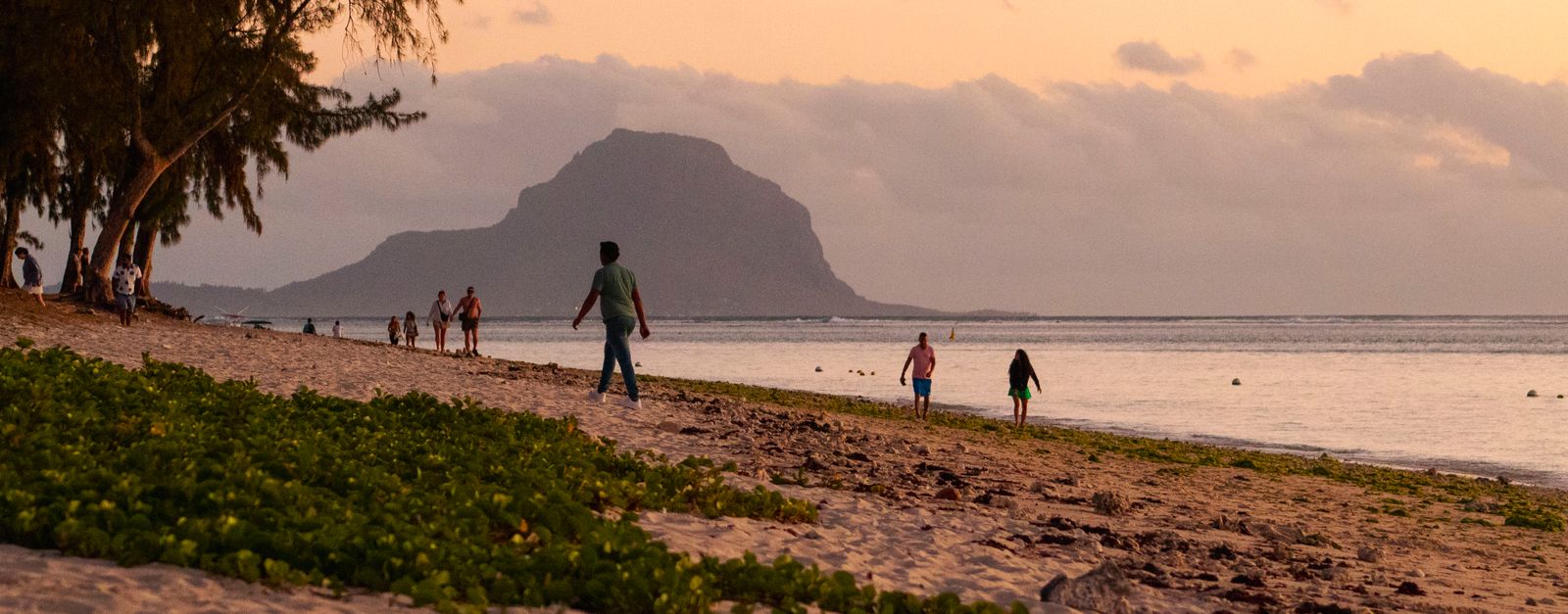 Experience a serene sunset at Flic en Flac Beach, Mauritius with Le Morne Brabant in the background.