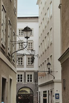 Discover the enchanting charm of a narrow alley in Salzburg, Austria, featuring classic street lamps and historic architecture.