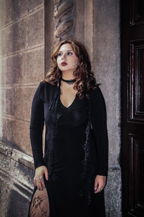 Free Woman in gothic attire standing against stone wall, conveying elegance and mystery. Stock Photo