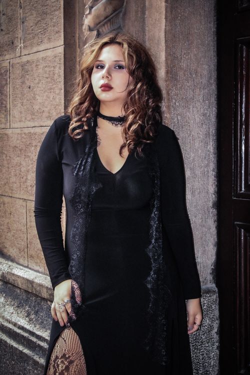 Free Portrait of a woman dressed in gothic fashion leaning against a textured wall. Stock Photo