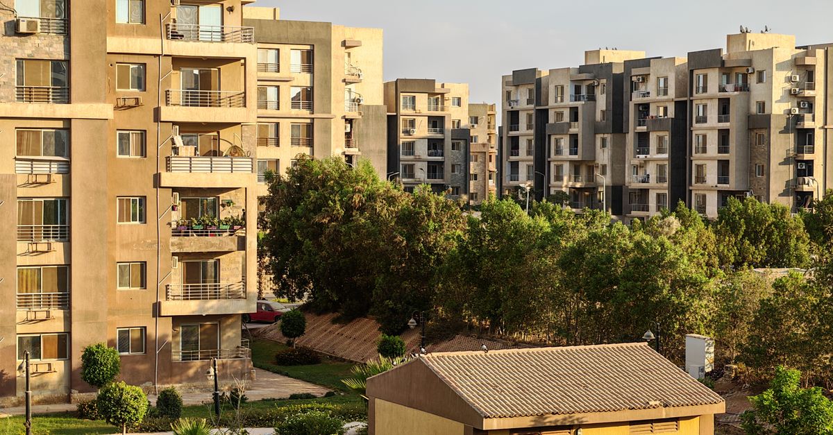 Sunlit view of modern apartment buildings surrounded by greenery in an urban neighborhood.
