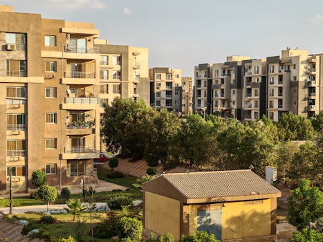 Sunlit view of modern apartment buildings surrounded by greenery in an urban neighborhood.