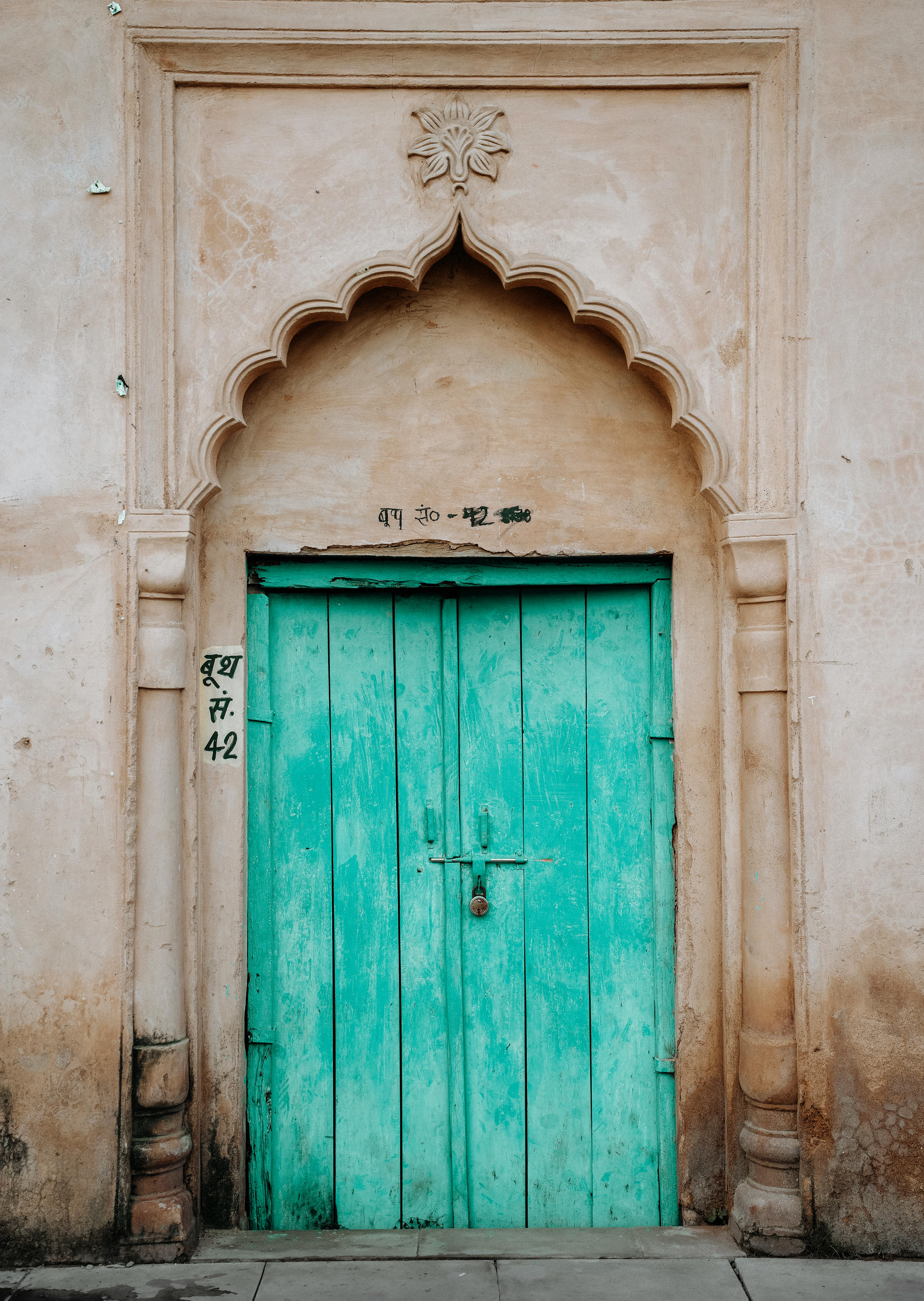 Ornate turquoise door with arch in Lucknow, India showcasing traditional architecture.