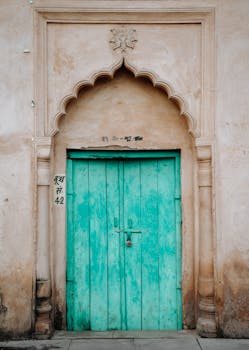 Ornate turquoise door with arch in Lucknow, India showcasing traditional architecture.