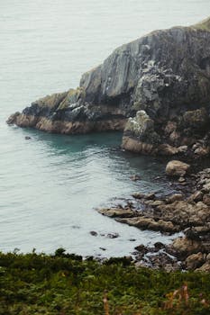 宁静的岩石悬崖位于平静的海洋上，提供宁静的沿海景观