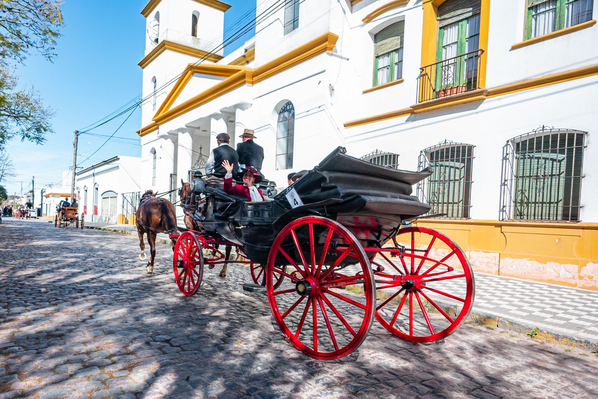 Vintage horse-drawn carriage travels down a cobblestone street in Chascomús, capturing historical charm.