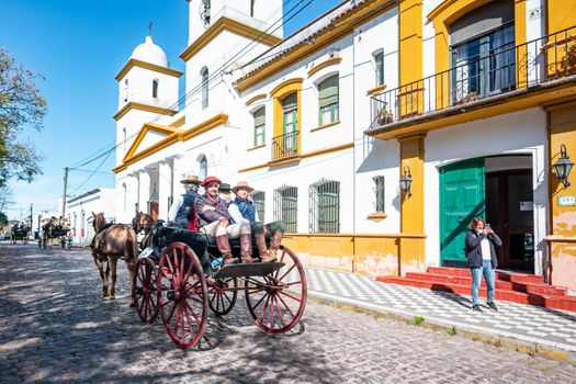 A traditional horse-drawn carriage on a sunny street in Chascomús, showcasing historic architecture and cultural charm.