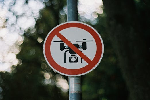 Circular no drone zone sign attached to a pole in a forest with a blurred bokeh background.