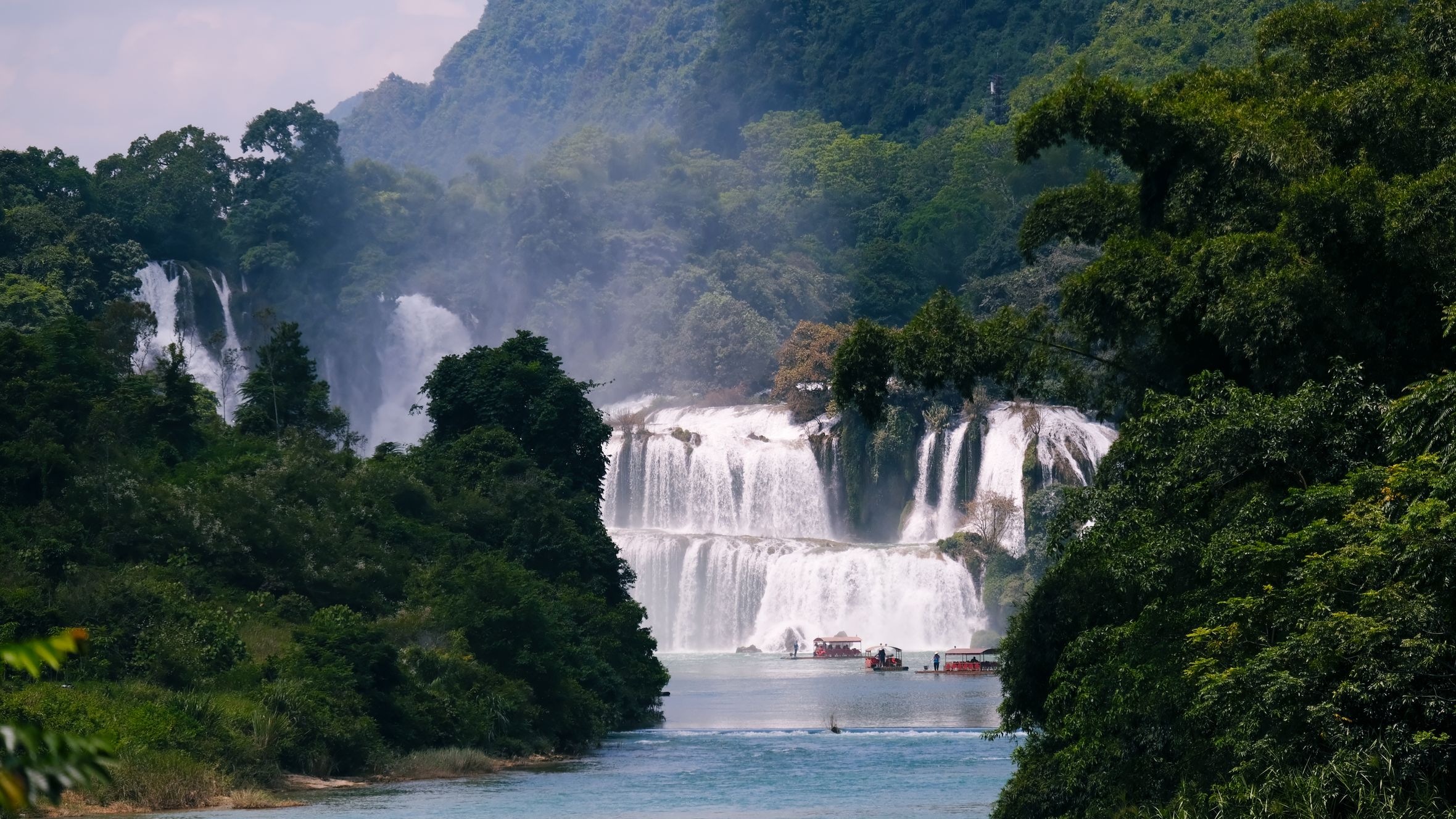 Majestic view of Ban Gioc Waterfall surrounded by vibrant foliage in Vietnam, perfect for travel inspiration.