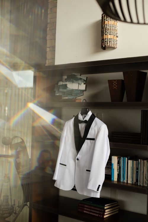 Free Stylish white tuxedo with black lapel hanging indoors reflecting light through a window. Stock Photo