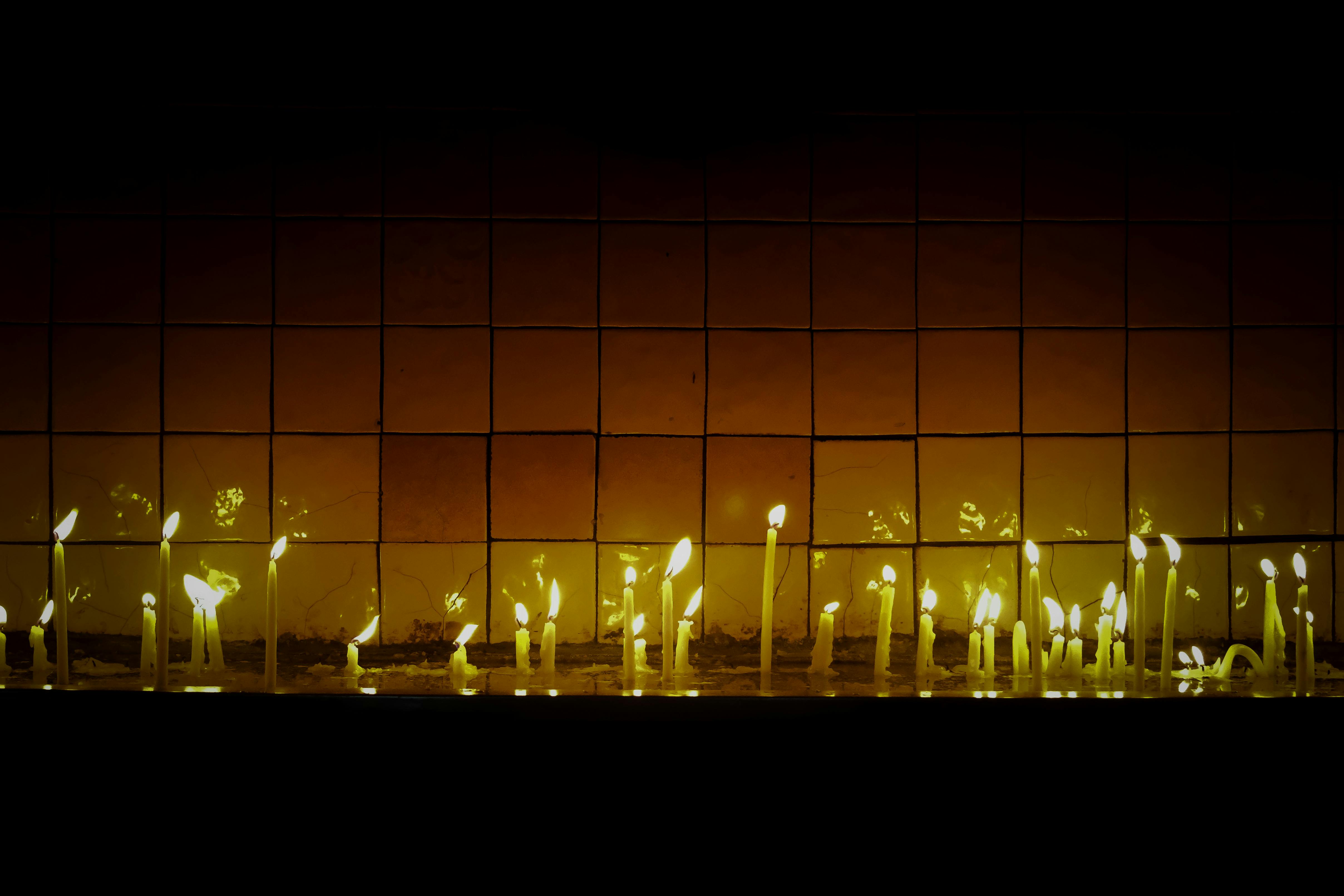 免費 一排蠟燭在瓷磚牆上投射出溫暖的倒影，營造出寧靜而沉思的氛圍。 圖庫相片