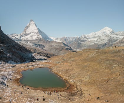 Stunning alpine landscape of the Matterhorn in Zermatt, with a serene lake and vibrant scenery under a clear sky.