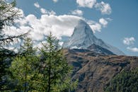 在瑞士的采尔马特，晴朗的蓝天下，马特宏峰和郁郁葱葱的树木构成了令人叹为观止的景色
