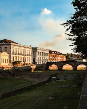 古老的殖民建筑旁，宁静的景色中，夕阳的温暖光芒洒在一座石桥上