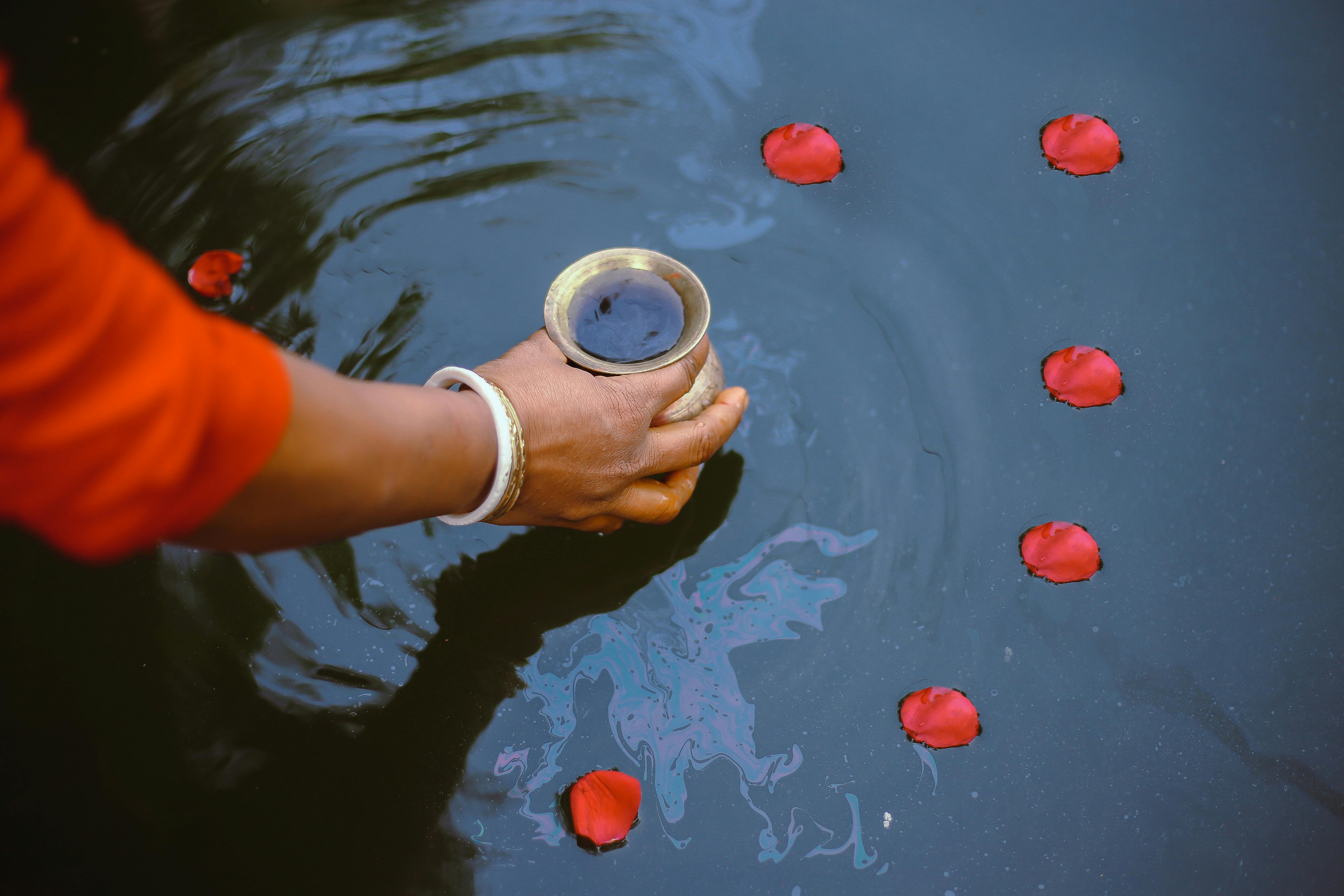 person holding gold jar with liquid inside