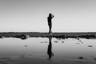 在海滩的水坑中，一张黑白照片静静地反射着宁静和平静