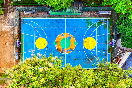 Aerial shot of a colorful basketball court in a lush setting, showcasing vibrant colors from above.