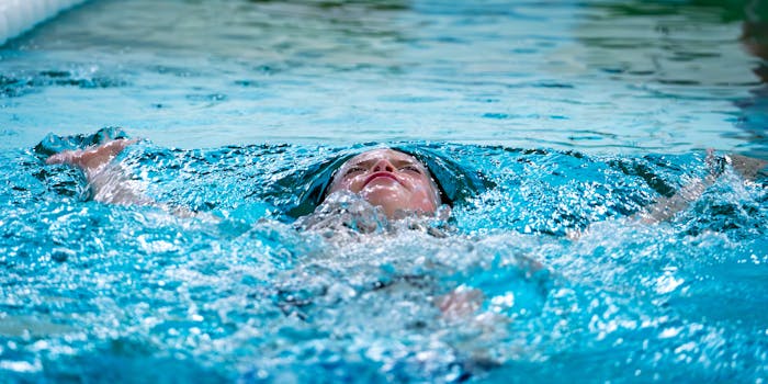 A young child enjoys swimming underwater, surrounded by sparkling blue water.
