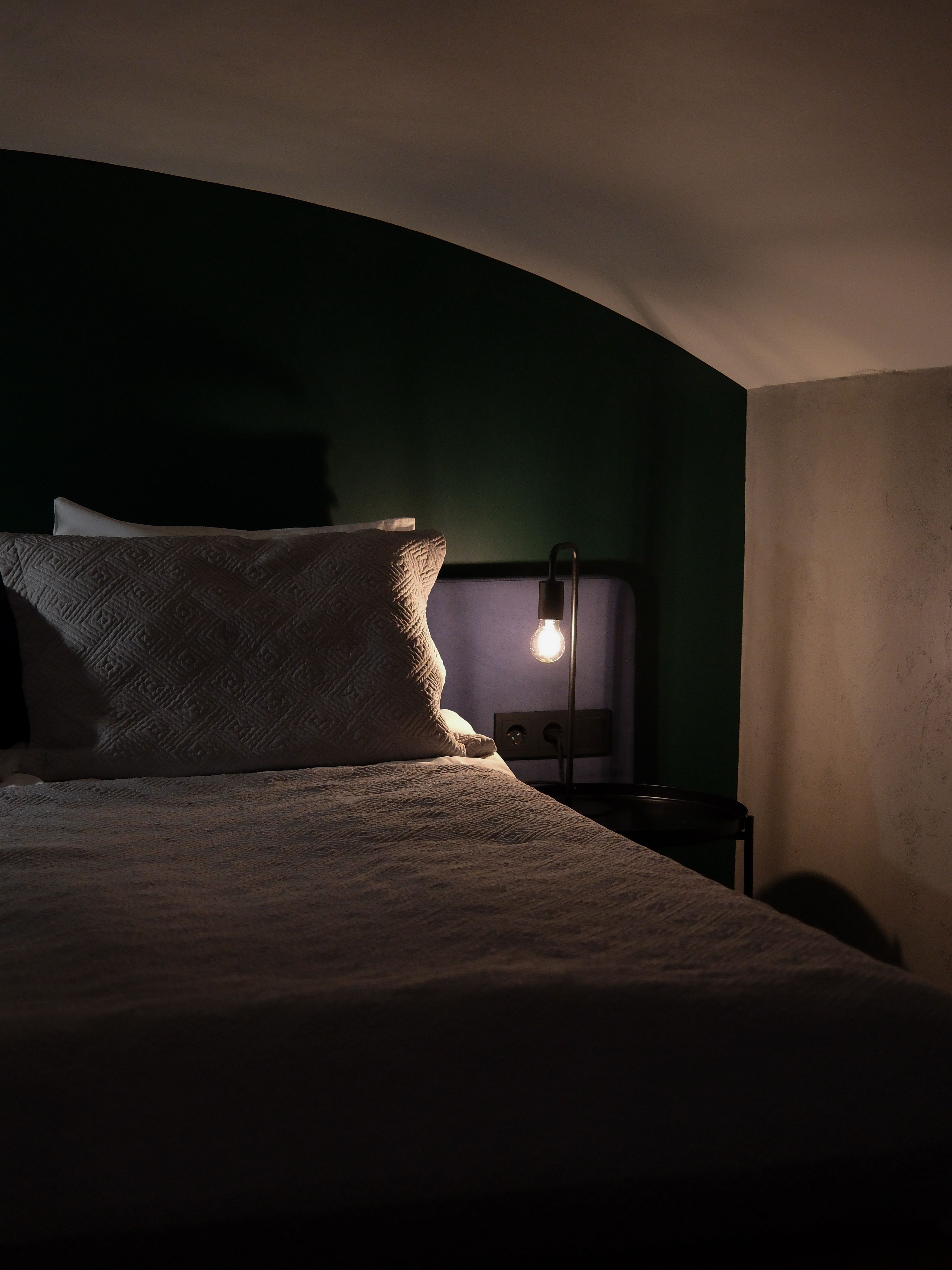 Comfortable bedroom with soft lighting and cozy atmosphere, featuring a bed and a lit bedside lamp.