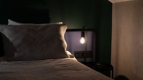 Comfortable bedroom with soft lighting and cozy atmosphere, featuring a bed and a lit bedside lamp.