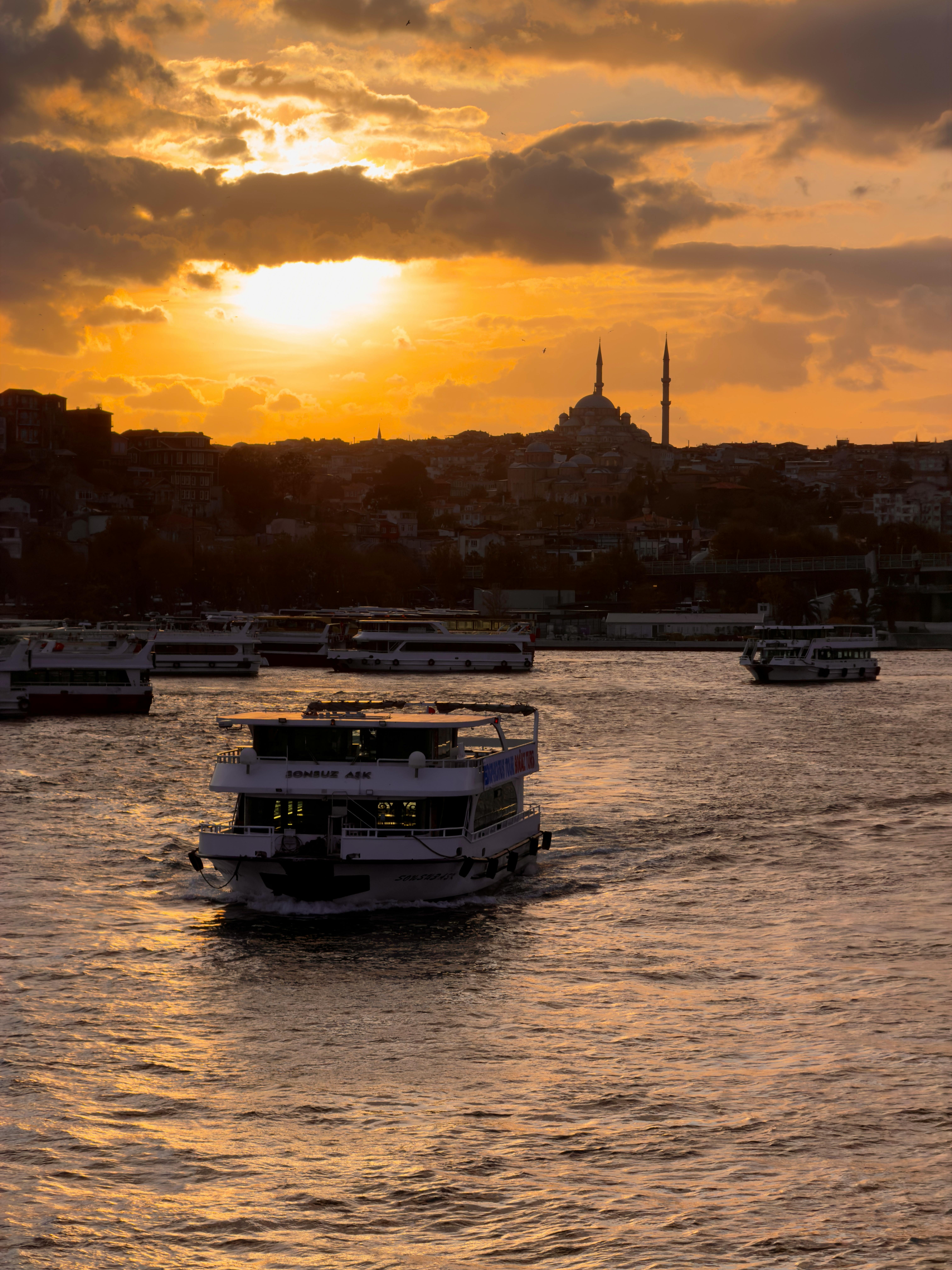 小船在博斯普鲁斯海峡巡航，日落时分与伊斯坦布尔的地平线和清真寺剪影相映成趣