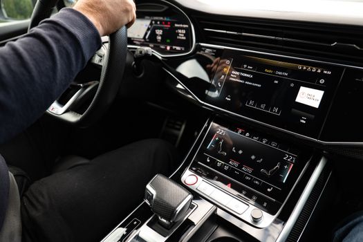 Close-up of modern car interior featuring digital displays and a driver holding the steering wheel.
