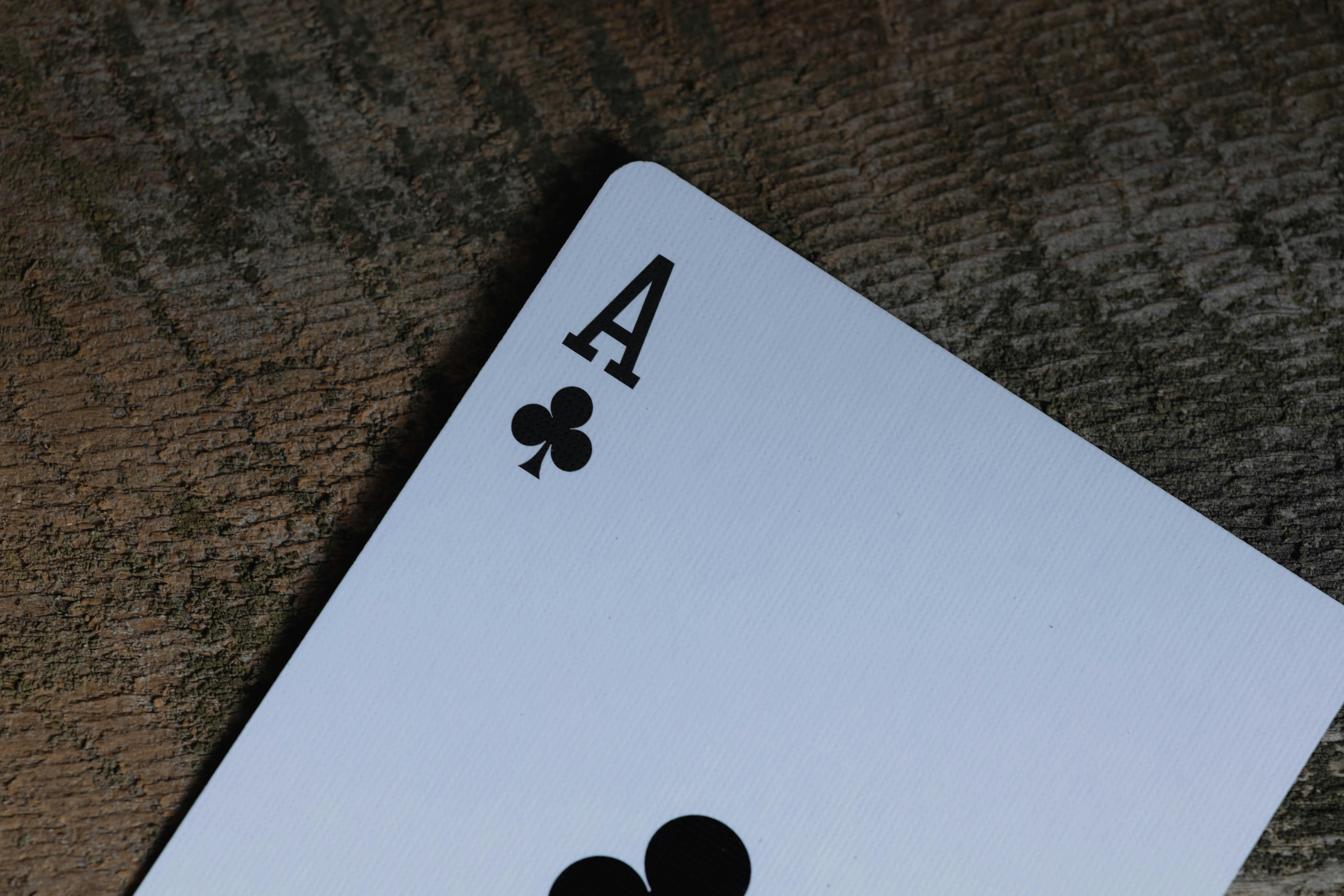 De franc As de cartes de trèvols sobre una superfície de fusta texturada, que evoca un ambient rústic i clàssic. Foto d'estoc