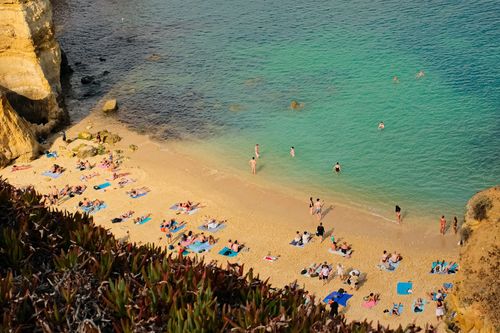 Free Discover the stunning Algarve coastline with sunbathers and turquoise waters at a beautiful Lagos beach. Stock Photo
