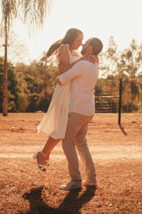 Free A couple shares a romantic moment outdoors in the warm glow of sunset. Stock Photo