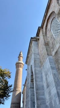 在清澈的蓝天下，清真寺的尖塔和大理石立面展现出建筑的优雅