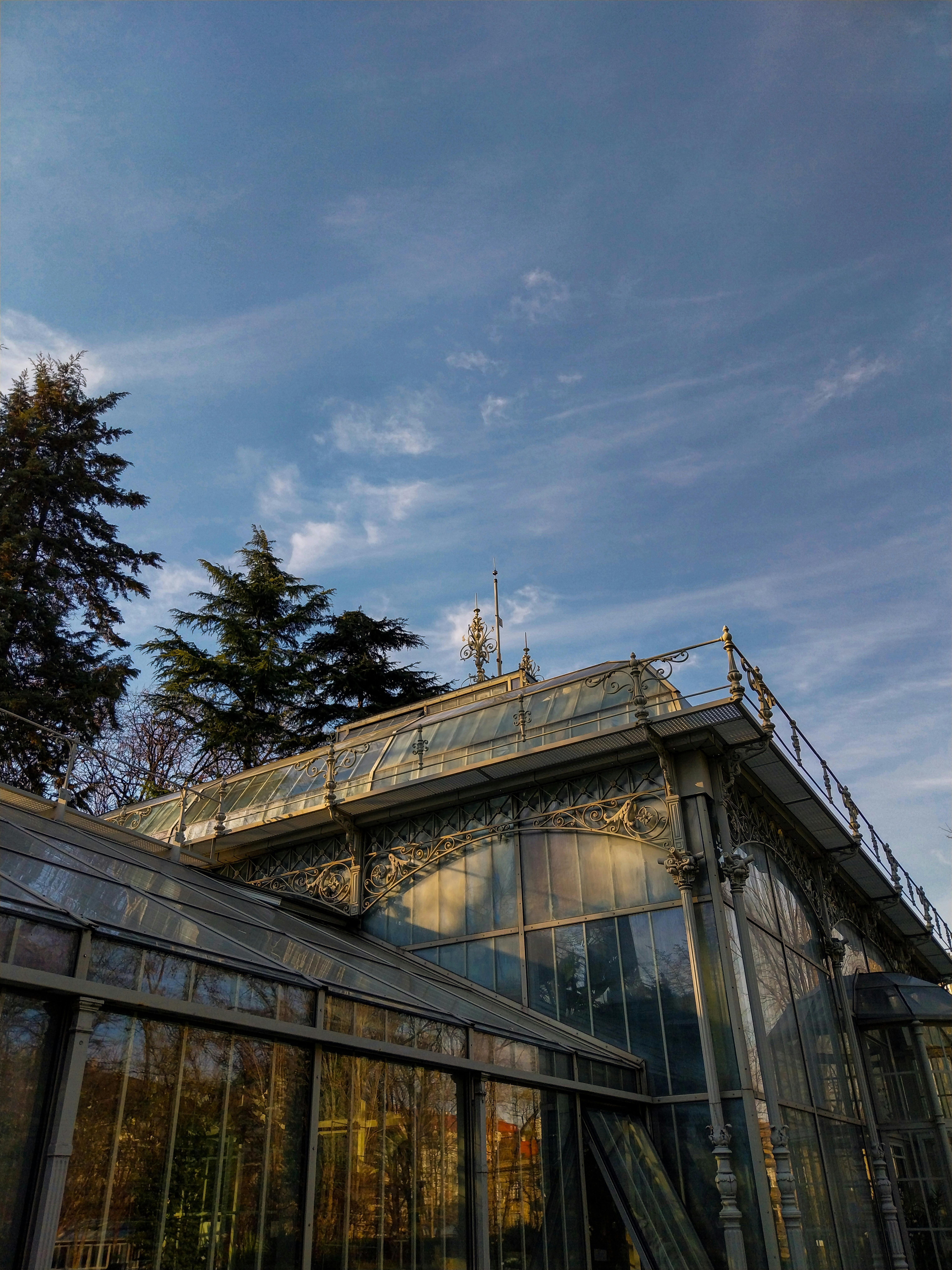 优雅的维多利亚式温室，拥有复杂的铁制品，映衬着清澈的蓝天