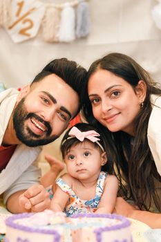 Cheerful parents with a baby celebrating her 6-month milestone.