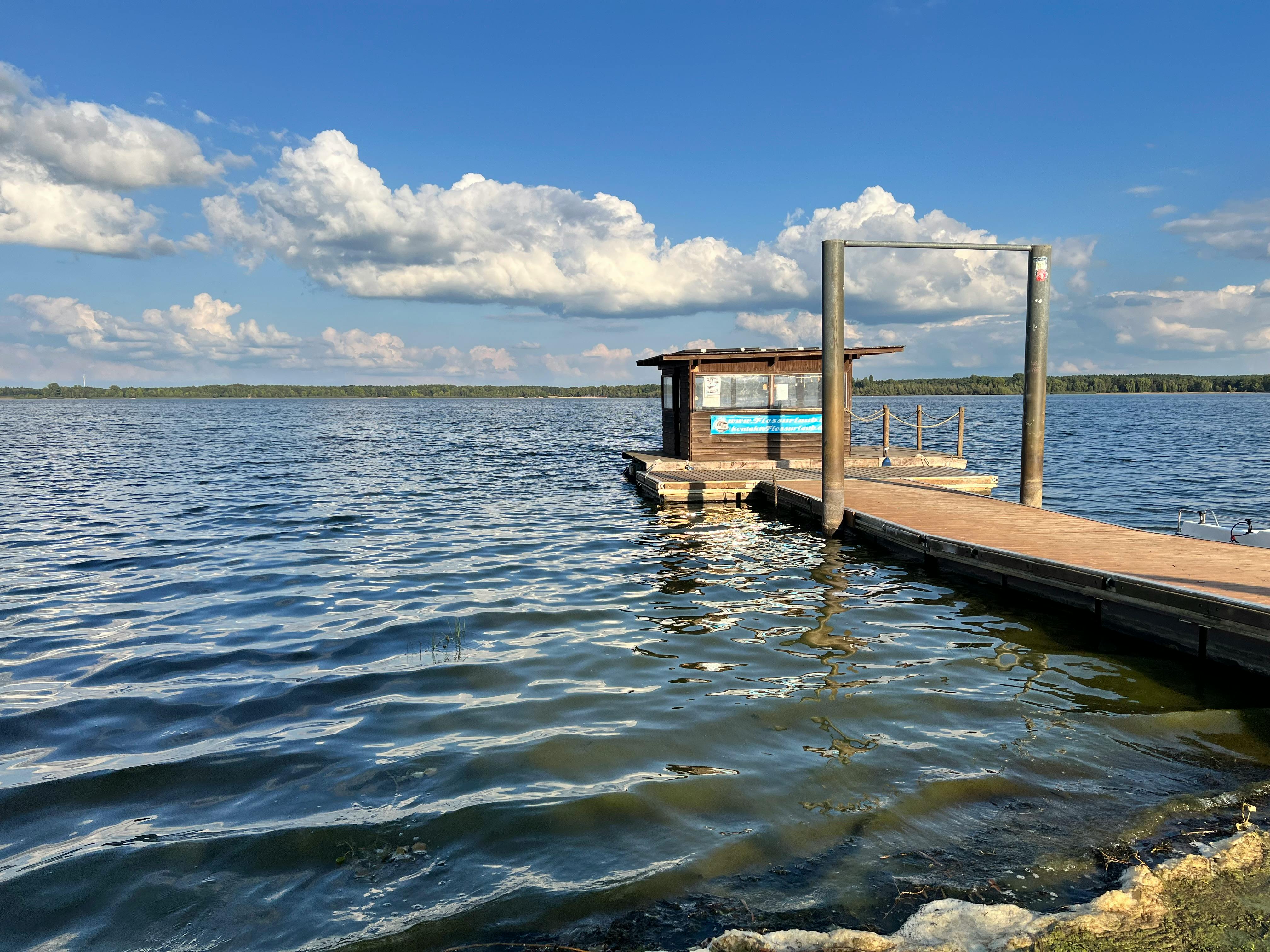 平静的湖面上漂浮着码头，蓝天如洗，头顶上飘浮着朵朵云
