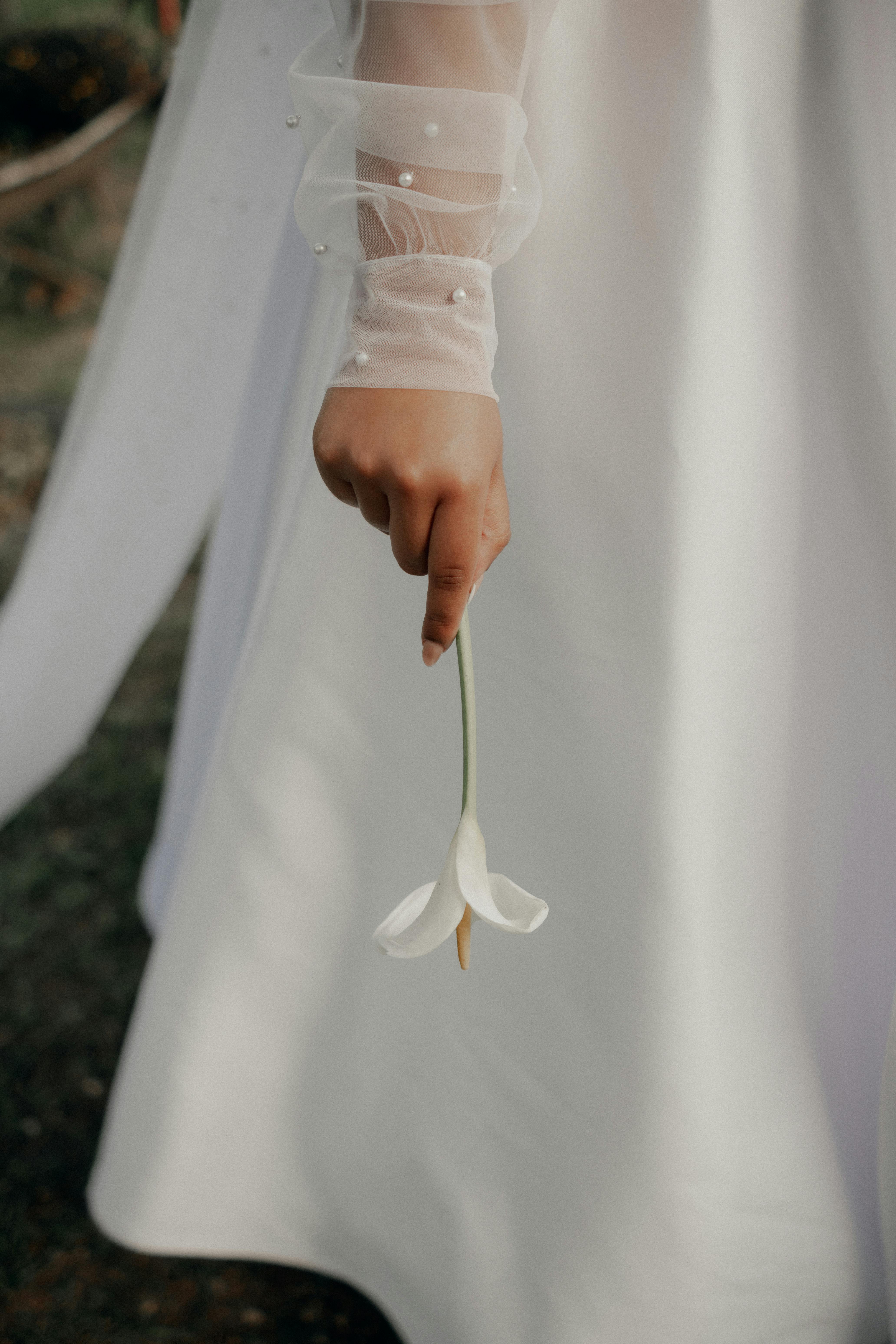 新娘手持白色马莲，柔和的焦点和温暖的色调展现出优雅与简约