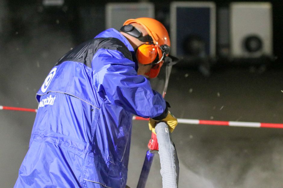 Industrial worker in protective gear using equipment, emphasizing safety in construction.