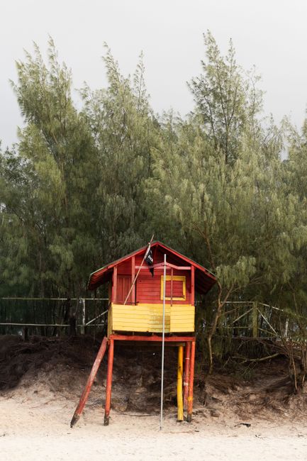 A vibrant lifeguard hut stands on a sandy beach in Florianópolis, Brazil.
