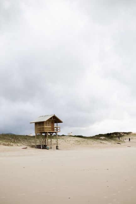 A serene lifeguard hut on a sandy beach in Florianópolis under cloudy skies.