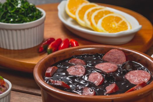 Traditional Brazilian feijoada with chorizo, orange slices, greens, and peppers.