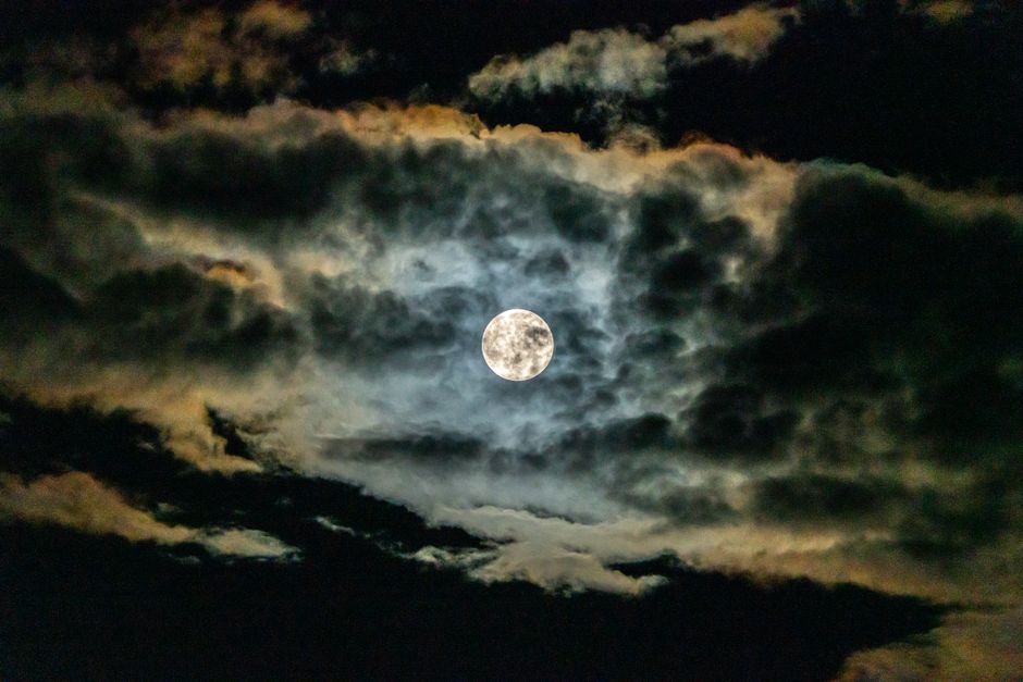 Una cautivadora luna llena brilla a través de dramáticas nubes nocturnas, creando una escena celestial mística y atmosférica.
