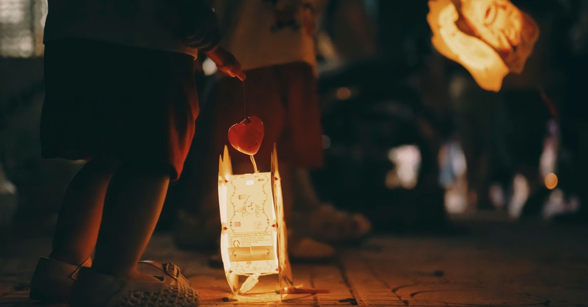 Children holding lit lanterns during a night festival, creating a warm and festive atmosphere.