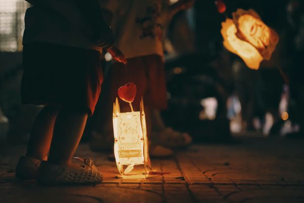 Children carrying lit lanterns at a night festival — photo by Tong Quan on Pexels