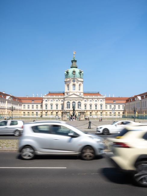 Blurred cars passing in front of Charlottenburg Palace, Berlin, on a sunny day.
