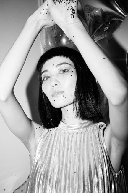 Black and white portrait of a stylish woman posing with balloons in an artistic setting.